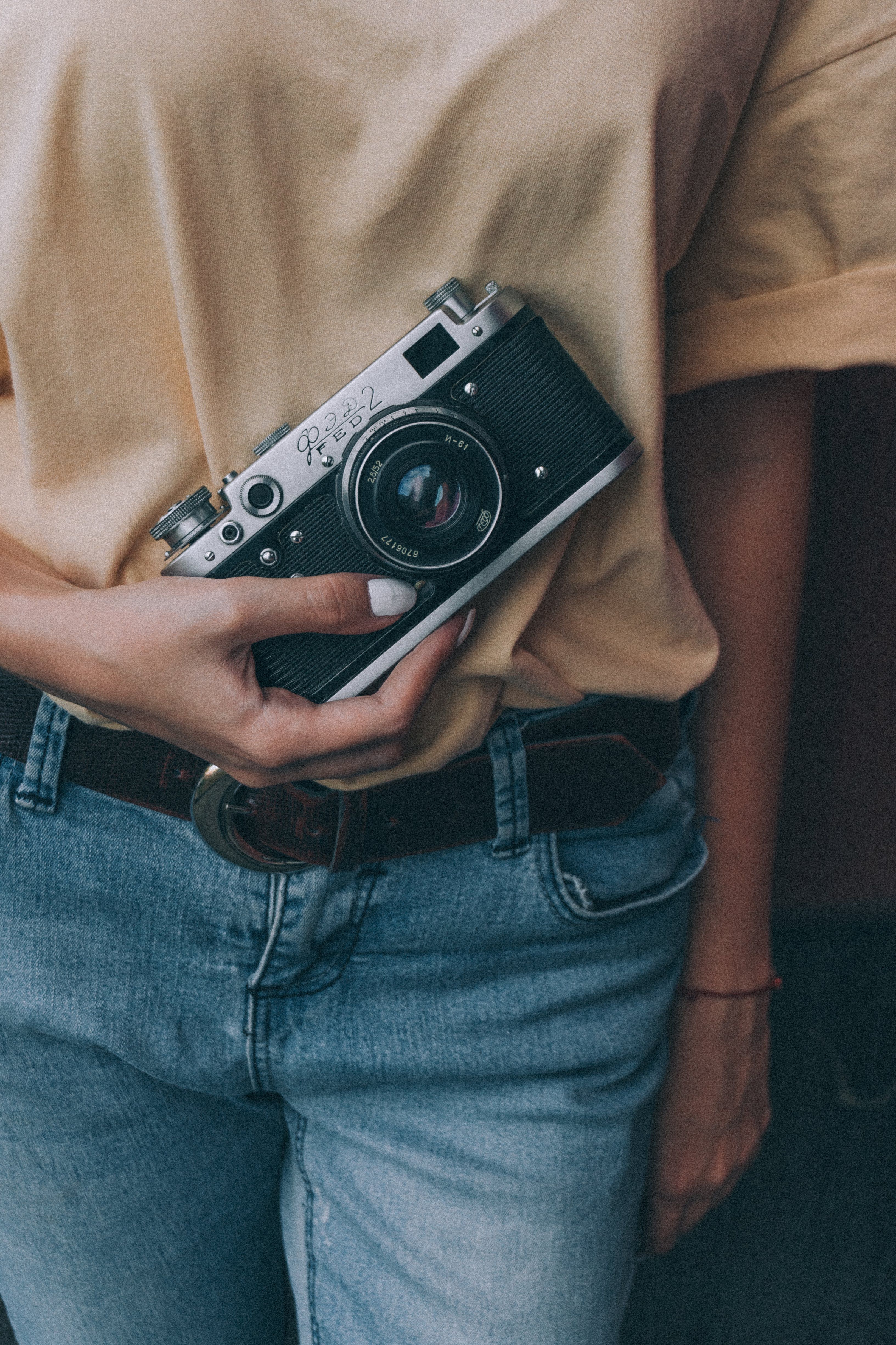 A person holding a vintage camera against denim and warm fabric