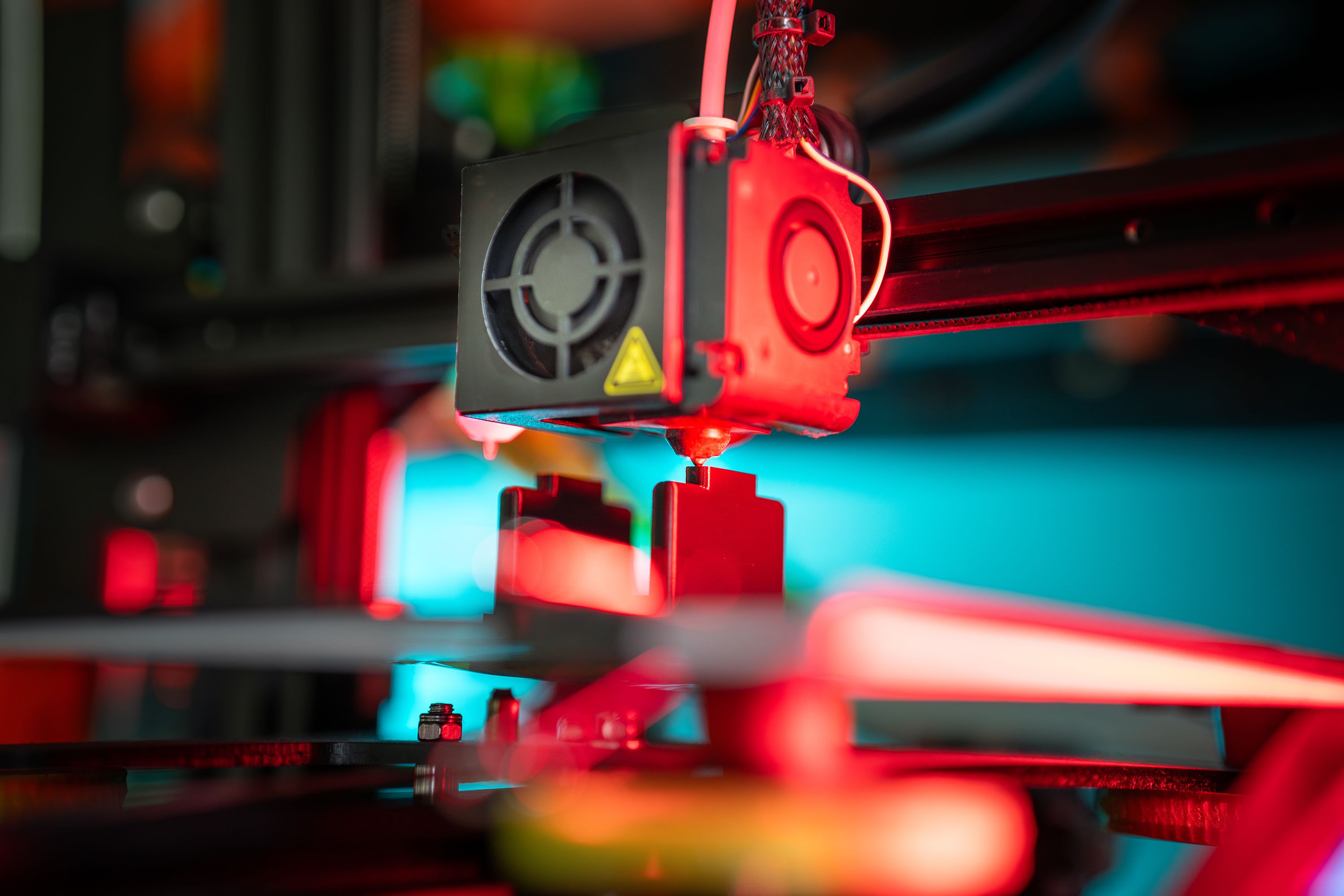 A close-up of a 3D printer with red and blue light