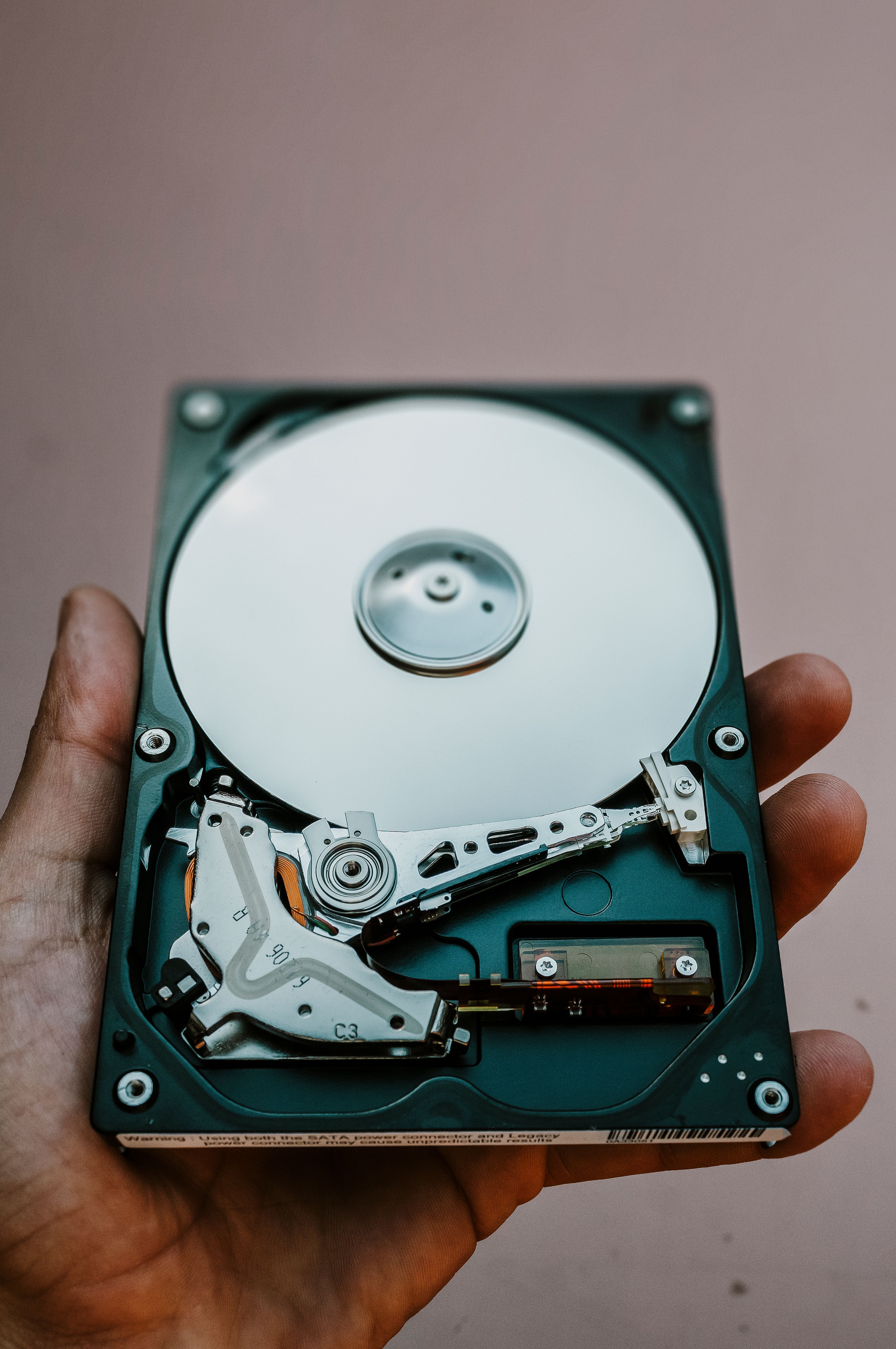 An exposed hard drive held in one hand
