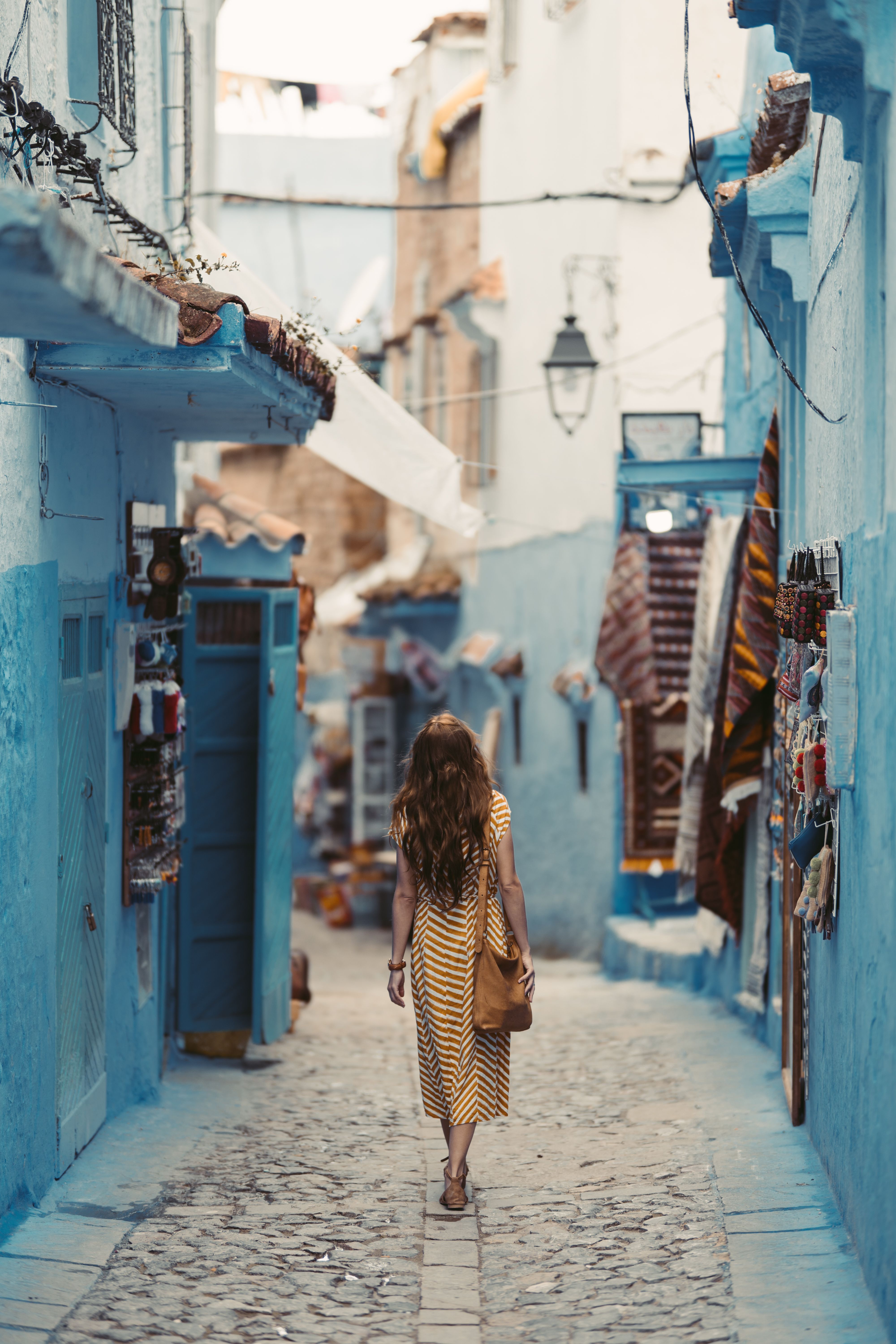 A traveler walking through a blue-painted city street